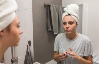 Frau cremt sich mit Retinol-Creme ein